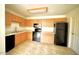 Galley kitchen with wood cabinets, black appliances, and tile floor at 14300 W Bell Rd # 444, Surprise, AZ 85374