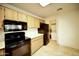 Kitchen boasts wood cabinets, black appliances, and access to laundry at 14300 W Bell Rd # 444, Surprise, AZ 85374