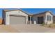 Front of the home with a two-car garage, brick driveway, and landscaping at 21664 E Roundup Way, Queen Creek, AZ 85142