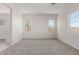 Empty living area with gray carpet and windows, view to kitchen at 21664 E Roundup Way, Queen Creek, AZ 85142