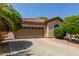 Exterior view of a beige house with a brown garage door and mature landscaping at 2074 E Hulet Pl, Chandler, AZ 85225