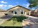 Artificial turf backyard with a covered patio, gravel, and a small walkway at 42054 W Cheyenne Dr, Maricopa, AZ 85138
