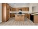 Kitchen with an island, wood cabinets, and light-colored laminate flooring at 42054 W Cheyenne Dr, Maricopa, AZ 85138