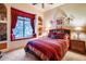 Bedroom with window seat, wood furniture, and red bedding at 8300 E Dixileta Dr # 253, Scottsdale, AZ 85266
