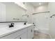 Clean white bathroom with black hardware, a double vanity, and tiled shower at 16348 W Avenida Del Sol --, Surprise, AZ 85387
