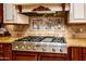 Gas cooktop with griddle and custom tile backsplash in a luxury kitchen at 9233 S Krista E Dr, Goodyear, AZ 85338
