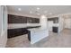 Modern kitchen with dark cabinets, granite island, and tile flooring at 18128 W Daley Ln, Surprise, AZ 85387