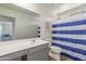 Bathroom with grey vanity, white toilet and blue striped shower curtain at 16245 W Culver St, Goodyear, AZ 85338