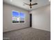 Spacious bedroom with carpeted floor, large window, and ceiling fan at 19617 N 39Th Dr, Glendale, AZ 85308