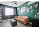 Cozy home office features a brown couch, built-in shelving, and a green accent wall at 19731 N Ben Ct, Maricopa, AZ 85138