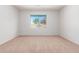 Well-lit bedroom with neutral walls and carpeting, featuring a window with backyard view at 10908 E Olla Ave, Mesa, AZ 85212