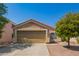Tan stucco house with a double-car garage and a small, landscaped front yard at 23780 W Tonto St, Buckeye, AZ 85326