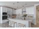 Modern kitchen with white cabinets, island, and herringbone backsplash at 16172 W Alameda Rd, Surprise, AZ 85387
