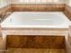 Soaking tub with tiled surround and raised platform at 19950 W Cambridge Ave, Buckeye, AZ 85396