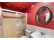 Bathroom with shower, red walls, and oval mirror at 18256 N 75Th Ave, Glendale, AZ 85308