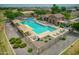 Community pool with a stone building, umbrellas, and surrounding landscaping at 18465 N Falcon Ln, Maricopa, AZ 85138