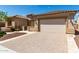 Front view of a beige house with a large garage and brick driveway at 26496 W Lone Cactus Dr, Buckeye, AZ 85396