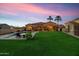 Peaceful backyard retreat with a sparkling pool and grassy lawn at sunset at 8325 W Cantera Ave, Peoria, AZ 85383