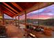 Covered porch with wooden flooring, sunset view, and potted plants at 1310 Kenrick Dr, Wickenburg, AZ 85390