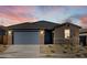 Attractive one-story home with gray garage doors and desert landscaping at dusk at 20336 N 224Th Dr, Surprise, AZ 85387