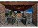 Covered patio with fireplace, seating area, and stunning sunset view at 10911 E Taos Dr, Scottsdale, AZ 85262