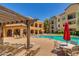 Community pool with patio furniture and red umbrella at 14575 W Mountain View Blvd # 221, Surprise, AZ 85374