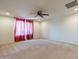 Spacious bedroom with carpeted floor, ceiling fan, and window with red curtains at 11040 E Tumbleweed Ave, Mesa, AZ 85212