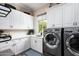 Laundry room with modern washer, dryer, and white cabinets at 19621 N 96Th Pl, Scottsdale, AZ 85255