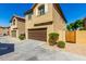 Two-story tan home with a brown garage door and gated driveway at 851 E Agua Fria Ln, Avondale, AZ 85323