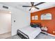 Bright bedroom with a full bed, ceiling fan, and an orange accent wall at 2616 S Extension Rd, Mesa, AZ 85210