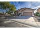 Single-story house with tan exterior, two-car garage, and tree in front at 10801 W Palm Ln, Avondale, AZ 85392