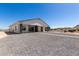 Home's back exterior showcasing a covered patio and gravel driveway at 27502 N Freedom St, San Tan Valley, AZ 85144