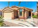 Exterior view of a tan house with a double-car garage and desert landscaping at 18112 W Spencer Dr, Surprise, AZ 85374