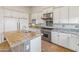 Elegant kitchen with granite island, white cabinets, and stainless steel appliances at 41253 N Whistling Strait Ct, Anthem, AZ 85086