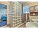 Bathroom with double vanity, glass block shower, and view of bedroom at 6614 W Sweetwater Ave, Glendale, AZ 85304