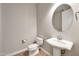 Clean bathroom with pedestal sink, toilet, and oval mirror at 26886 N 90Th Ave, Peoria, AZ 85383