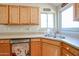 Bright kitchen featuring double sink, wood cabinets, and corner window at 26028 N 66Th Dr, Phoenix, AZ 85083