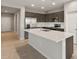 Modern kitchen with an island, dark cabinetry, white quartz countertops, and stainless steel appliances at 17798 W Encinas Ln, Goodyear, AZ 85338