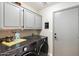 Bright laundry room with gray cabinets, LG washer and dryer, and a door at 14194 W Mountain Laurel Trl, Surprise, AZ 85374