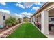 Landscaped backyard with grassy lawn, covered patio, and stone wall at 14194 W Mountain Laurel Trl, Surprise, AZ 85374
