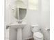Clean bathroom with pedestal sink, toilet, and round mirror at 7311 N 90Th Ave, Glendale, AZ 85305