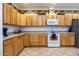 Bright kitchen with light wood cabinets, white appliances, and a breakfast bar at 8183 W Raven Dr, Arizona City, AZ 85123