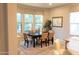 Formal dining room with a dark wood table, six beige chairs, and large windows at 27002 W Oraibi Dr, Buckeye, AZ 85396