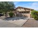 Tan house exterior with a two-car garage, landscaping, and desert-like surroundings at 1448 E Poncho Ln, San Tan Valley, AZ 85143