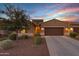 Tan stucco home with two car garage and desert landscaping at 41692 W Monsoon Ln, Maricopa, AZ 85138