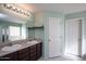 Main bathroom with double vanity, large mirror, and light green walls at 6129 S 255Th Dr, Buckeye, AZ 85326