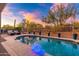 Sunset view over the backyard pool and patio area with string lights at 7056 E Mighty Saguaro Way, Scottsdale, AZ 85266