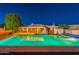 Night view of expansive backyard pool with pergola and outdoor kitchen area at 9645 E Brown Rd, Mesa, AZ 85207