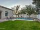 Inviting backyard with a sparkling pool, lush grass, and comfortable patio furniture at 1232 E Strawberry Dr, Gilbert, AZ 85298