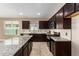 Modern kitchen with granite countertops and dark wood cabinets at 37784 W San Sisto Ave, Maricopa, AZ 85138